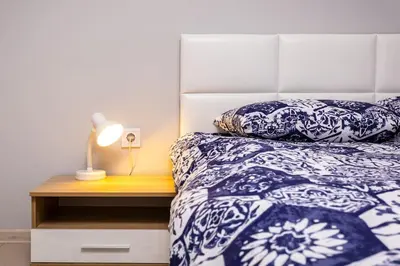 a bed with blue and white pillows and a night stand at Central apt 'SELIN' Walking distance to center in Plovdiv