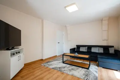 a living room with a black couch and a tv at 2-Bedroom Flat - Sunny Balcony in Plovdiv