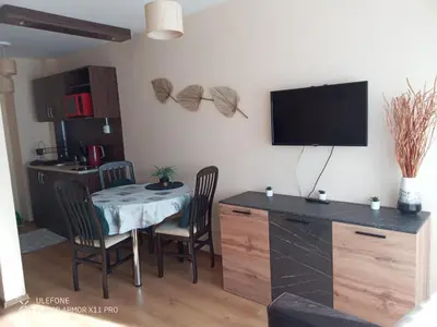 a living room with a table and chairs and a television at studio royal park bansko in Bansko