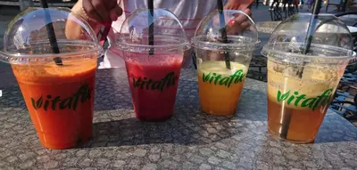 four different colored drinks in plastic cups on a table at Chic Urban Getaway in City Center by Flat Mаnager in Plovdiv