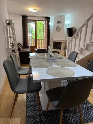 a dining room with a white table and chairs at Aparthotel Raikov Ski Lodge in Pamporovo