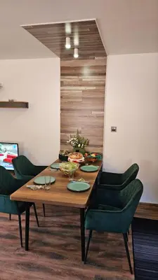 a wooden table with green chairs in a room at Aparthotel Raikov Ski Lodge in Pamporovo