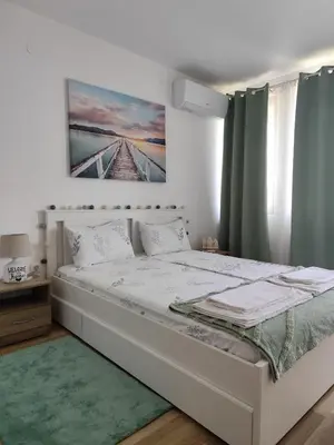 a bedroom with a white bed with a green rug at Sunny Hill Sandanski in Sandanski