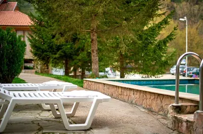 two white lounge chairs next to a swimming pool at Вълеви Къщи in Chiflik