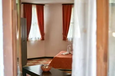 a room with a bed and a table and windows at Вълеви Къщи in Chiflik