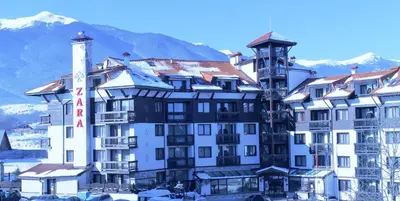 a large white building with a mountain in the background at Hotel Zara in Bansko