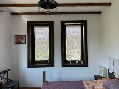 a bedroom with two windows and a bed with purple sheets at Guest House Opa in Smolyan