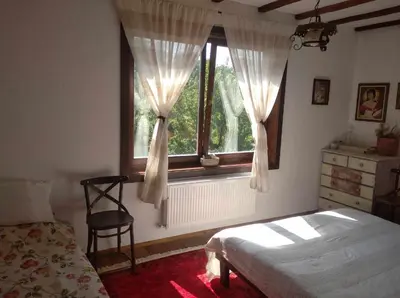a bedroom with a bed and a window with a chair at Guest House Opa in Smolyan