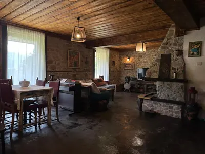 a living room with a table and a stone wall at Guest House Opa in Smolyan