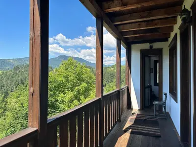 a porch with a chair and a view of the mountains at Guest House Opa in Smolyan
