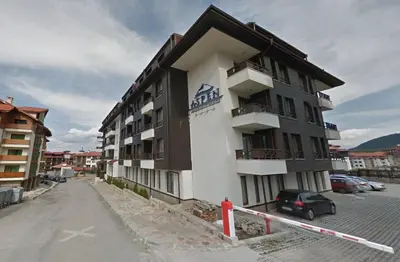 a building with a car parked in a parking lot at Ski Lift Apartment in Bansko in Bansko