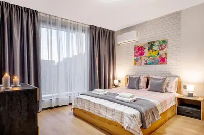 a bedroom with a bed and a large window at Best Guest 2 Apartments in Plovdiv