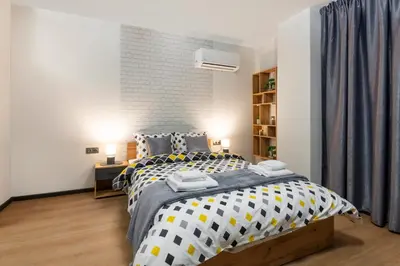 a bedroom with a large bed with yellow and gray pillows at Best Guest 2 Apartments in Plovdiv