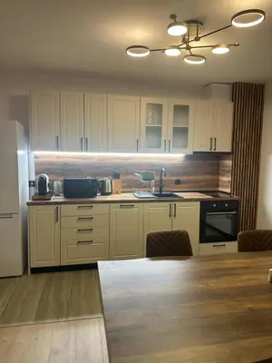 a kitchen with white cabinets and a sink and a table at MonarX Suites in Bansko