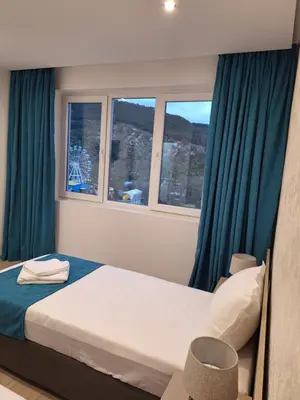 a bedroom with a bed and two windows at Sandanski park view in Sandanski