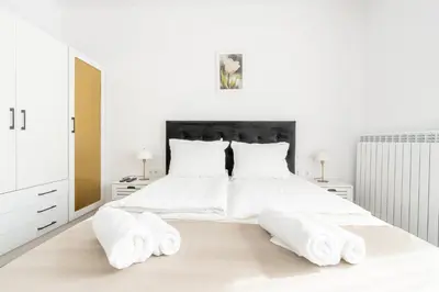 a white bedroom with a large white bed with two pillows at Apart house EMA 2 in Bansko
