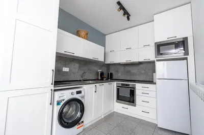 a kitchen with white cabinets and a washer and dryer at Apart house EMA 2 in Bansko