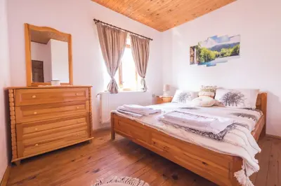 a bedroom with a bed with a dresser and a mirror at Stone house (Каменната къща) in Leshten