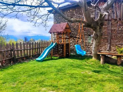 a playground with a slide and a tree at Stone house (Каменната къща) in Leshten
