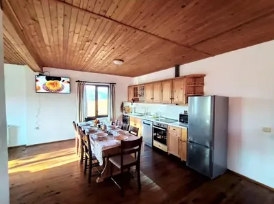 a kitchen with a table with chairs and a refrigerator at Stone house (Каменната къща) in Leshten