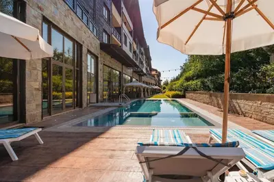 a pool with chairs and an umbrella next to a building at TERRA COMPLEX D5 - Private apartment - Golf, Skiing & SPA in Razlog