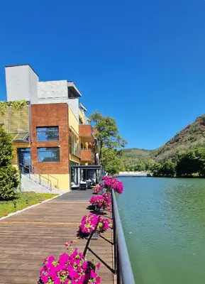 a building next to a lake with pink flowers at Waterside SPA Hotel in Ognyanovo