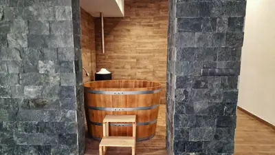 a wooden tub in a room with a stone wall at Waterside SPA Hotel in Ognyanovo