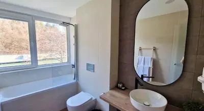a bathroom with a mirror and a tub and a sink at Waterside SPA Hotel in Ognyanovo
