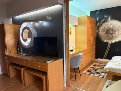 a room with a desk with a tv and a bedroom at City Sunrise in Sofia
