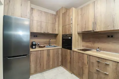 a kitchen with wooden cabinets and a stainless steel refrigerator at Cherkovna Residence Apartment plus GARAGE !!! in Sofia