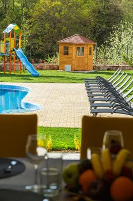 a table with chairs and a playground with a slide at ENEVI Guest Houses-Къщи за гости Еневи in Sandanski