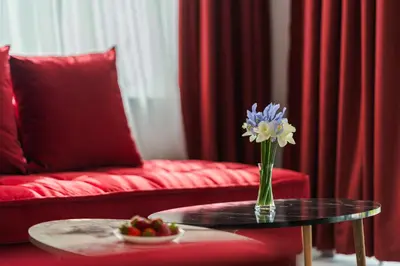 a vase of flowers on a table next to a red couch at ENEVI Guest Houses-Къщи за гости Еневи in Sandanski