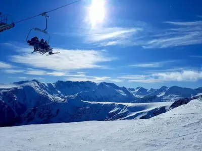 two people riding on a ski lift in the snow at TERRA COMPLEX B4 - Private apartment - Golf, Skiing & SPA in Bansko