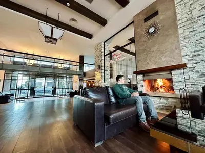 a man sitting on a leather couch in a living room with a fireplace at TERRA COMPLEX B4 - Private apartment - Golf, Skiing & SPA in Bansko