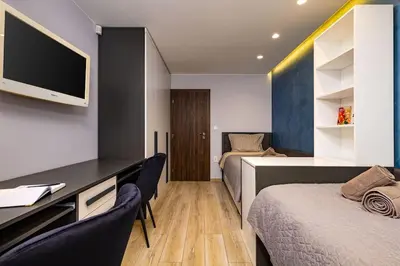 a room with two beds and a desk with a tv at Central Victoria Home 2-bedroom apt in Plovdiv