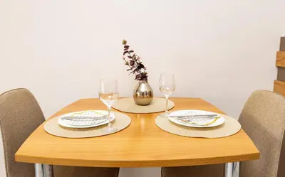 a wooden table with two glasses and a vase with flowers at Studio 'Ozi' quite place in Perfect Center in Plovdiv