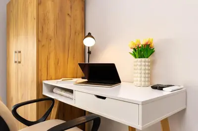 a white desk with a laptop and a vase of flowers at Studio 'Ozi' quite place in Perfect Center in Plovdiv