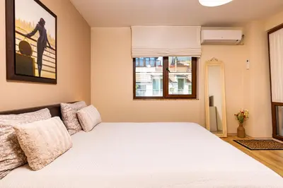 a bedroom with a bed and two windows at Beautiful apartment in the heart of Plovdiv in Plovdiv
