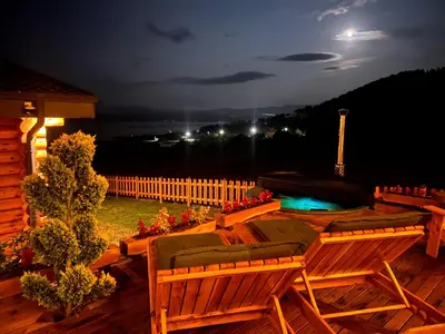a deck with chairs and a pool at night at Kare Luxury Chalets in Tsigov Chark
