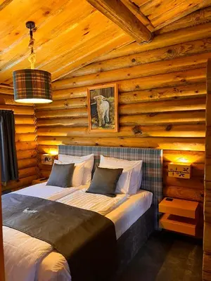 a bedroom with a bed in a log cabin at Kare Luxury Chalets in Tsigov Chark