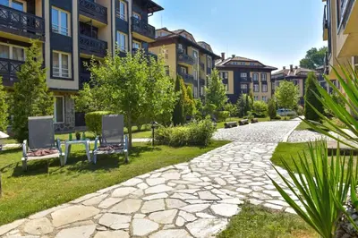 a stone walkway with two chairs and buildings at Апартамент-студио Б4-4-1 Божурленд in Bansko