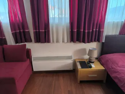 a living room with red curtains and a couch and a table at Апартамент-студио Б4-4-1 Божурленд in Bansko