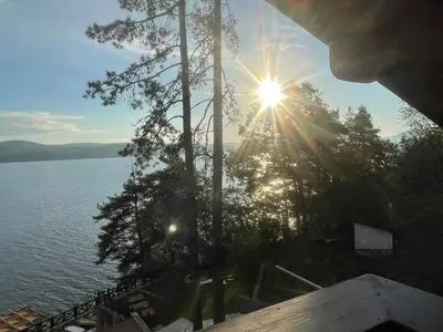 a view of a lake with the sun shining through trees at Villa Iskar Lake Residence by BookVillaBG in Shtarkelovo Gnezdo
