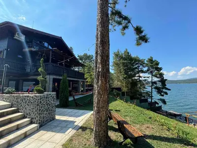 a wooden bench sitting next to a tree next to a building at Villa Iskar Lake Residence by BookVillaBG in Shtarkelovo Gnezdo