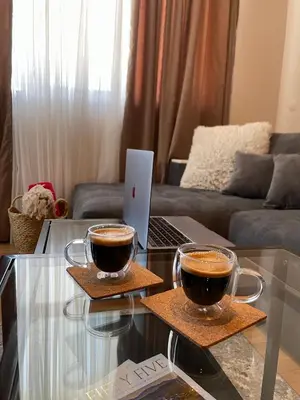 two cups of coffee on a glass table with a laptop at EVIAS Apartment in Sandanski