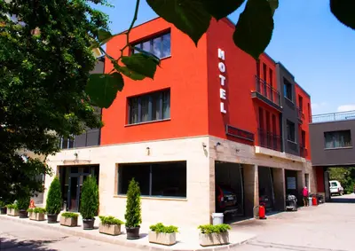 a red building with potted plants in front of it at Hotel Calipso Hotel in Sofia