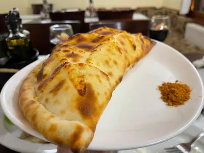 a slice of pizza on a white plate at The Castle Mountain Apartments in Pamporovo