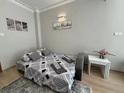 a white bedroom with a bed and a table at Garden view top center apart in Sofia