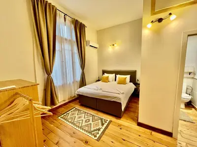 a bedroom with a bed and a large window at SKYLER VINTAGE APARTMENTS in Plovdiv
