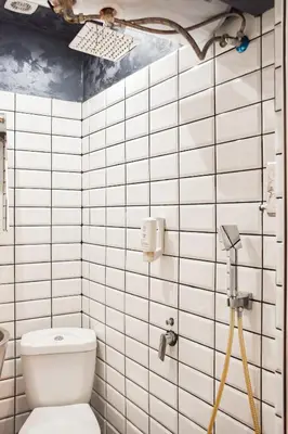 a white tiled bathroom with a toilet and a camera at Tsar Simeon 65 Studio (With Parking space) in Sofia